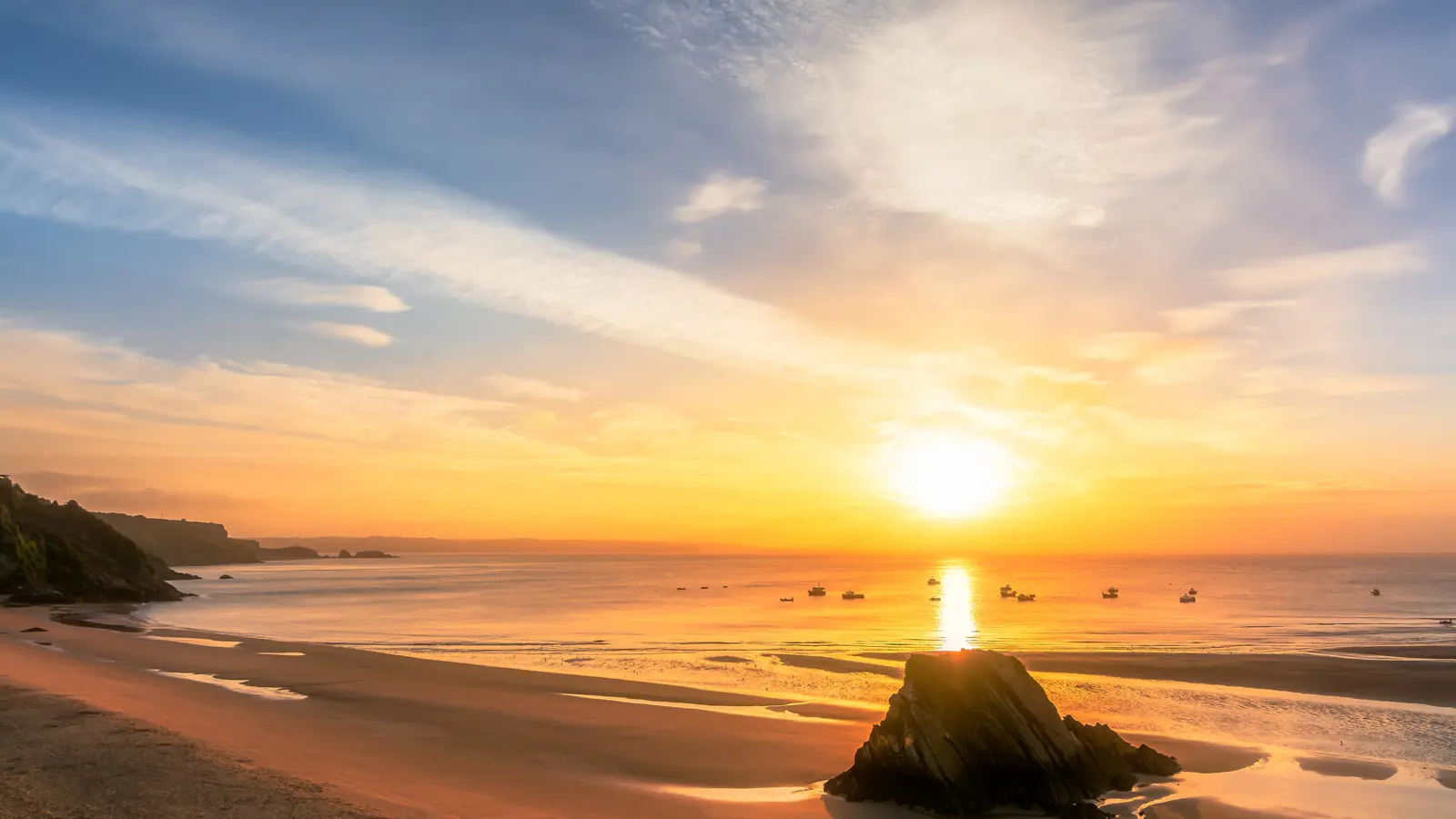 The sun setting over a large open bay on the Pembrokeshire coast