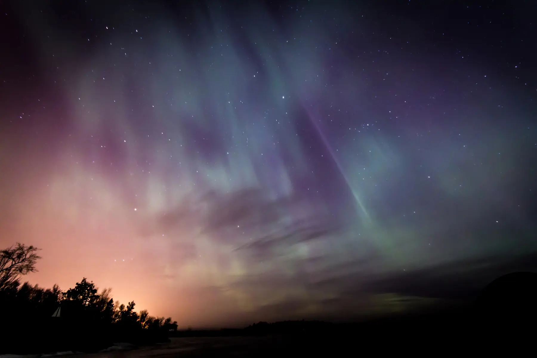 A dark starry sky with green waves lit up across it