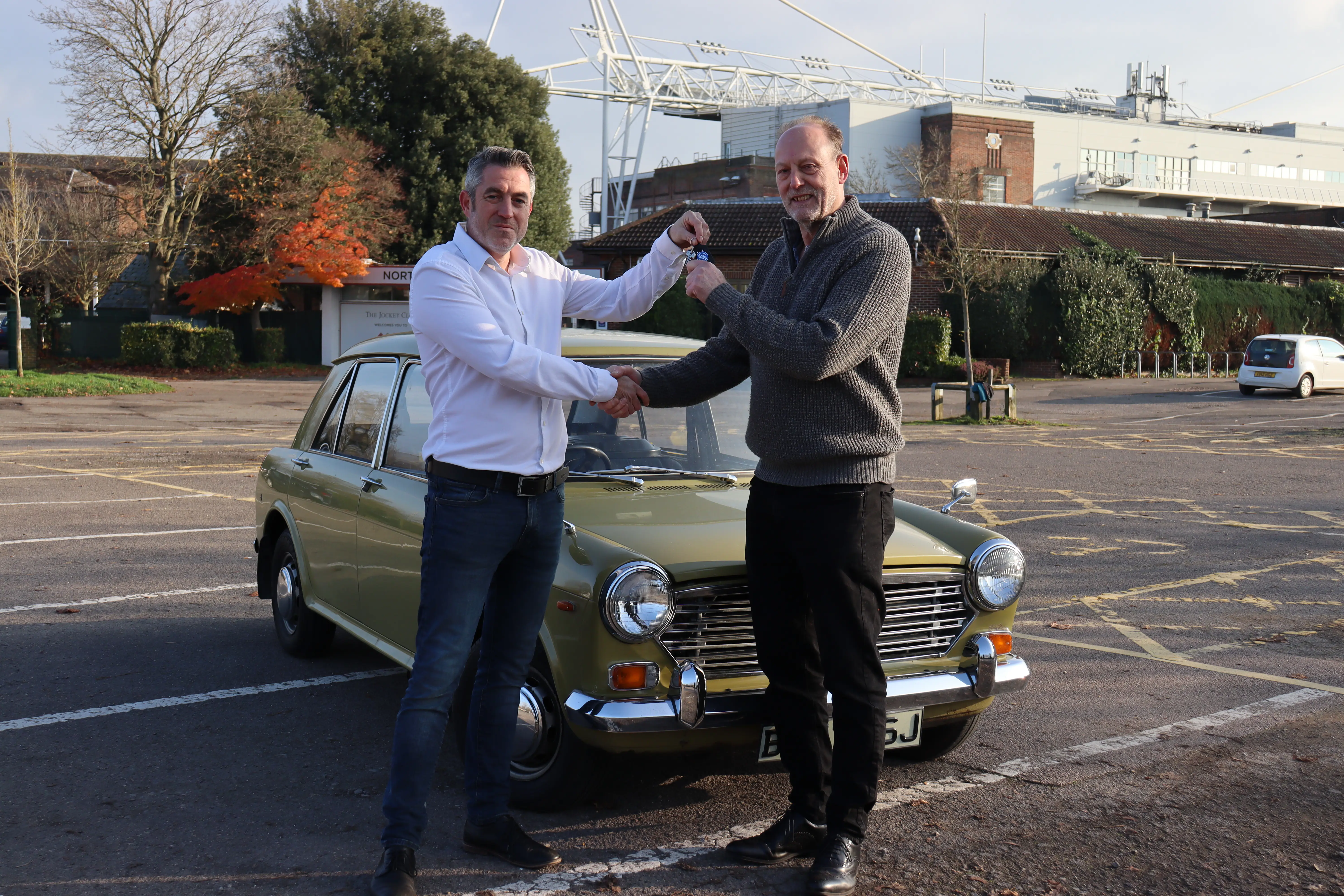 Men shaking hands by car