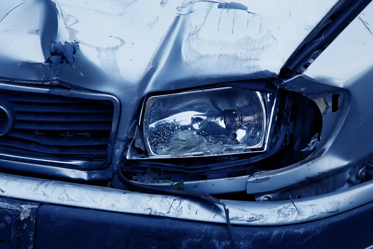 The crumpled front end and smashed headlight of a classic car after a crash