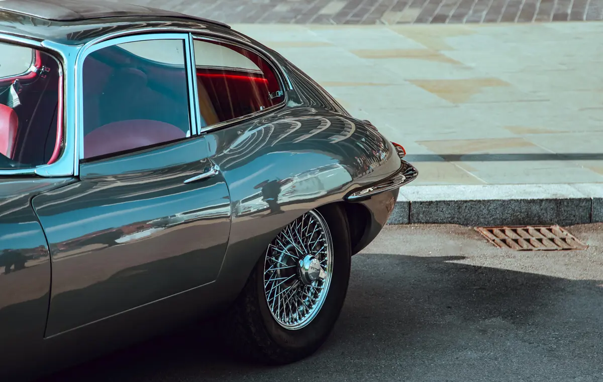 The rear end of a classic grey Jaguar E-Type with a red interior