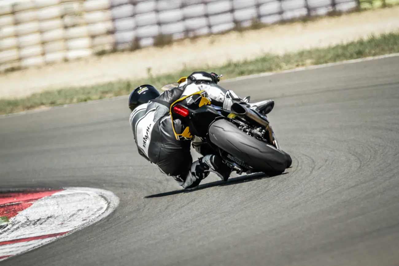 A motorcycle and racer leaning in as they turn round a bend on a racetrack